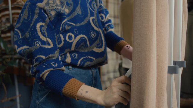 Young woman with prosthetic arm carefully steaming secondhand jacket, while working herr shift in modern thrift store