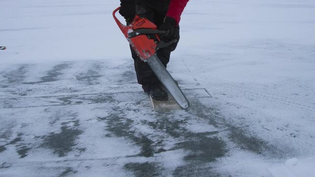 Orthodox priest in alaska cutting a rectangular hole in a frozen river for the epiphany ceremony