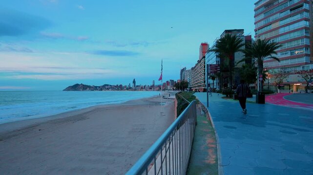 People walking on benidorm beach promenade at dawn