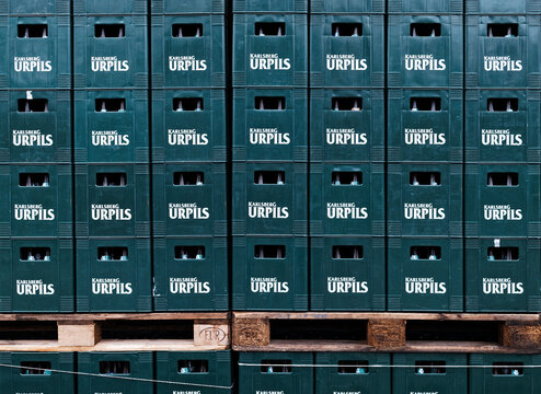Homburg (Saar), Germany - February 6, 2026: Stacked green plastic crates of Karlsberg Urpils beer on wooden pallets outside the brewery.