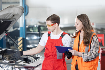 Male mechanic explains to female client cost of servicing car at service center