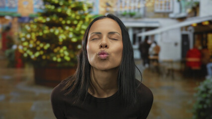Obraz premium Woman smiling joyfully in a festive outdoor street setting with christmas lights highlighting the background.
