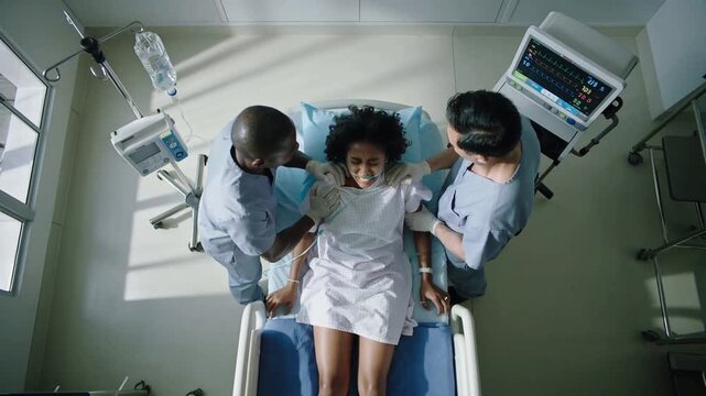 Medical team performing childbirth delivery in hospital room with woman patient, doctors assisting and supporting during labor and birth process.