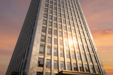 Modern building stands tall with sunlight reflecting off its windows at sunset in an urban area