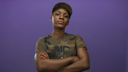 Woman in camouflage uniform crosses arms showing military dog tags in studio and gazes ahead with a...