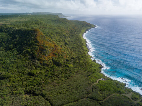Aerial view of the rugged coastline where verdant cliffs meet the turquoise sea, Guam, United States.
