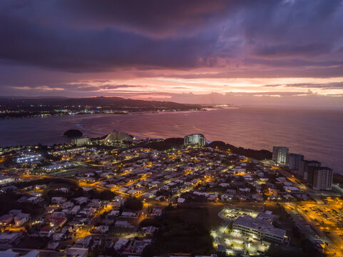 Aerial view of Tumon Bay's lights twinkle against the darkening sky meeting the tranquil, deep blue sea, Tamuning, Tamuning, Guam.