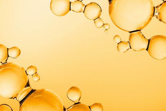 Abstract golden oil molecules floating on warm background. 3D render of luxury cosmetic serum or vitamin liquid with glossy transparent spheres, molecular structure, and copy space.