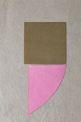 brown square and pink paper segment on textured brown ground
