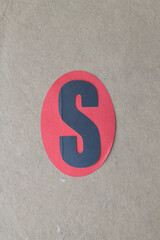 the letter s on a red paper oval 