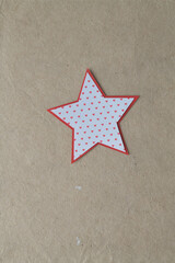 isolated paper star with heart pattern and red border on brown