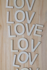 the word love composed with wooden letters repeated on a pine surface
