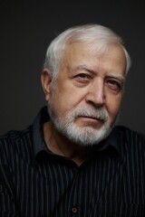 Obraz premium Older man poses for a close-up portrait with a focused expression in a dark setting