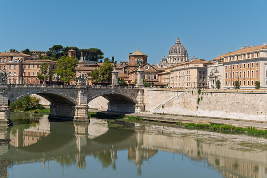 Italy - Rome - Tiber River - Peaceful waters mirror historic bridge arches with St Peter's Basilica dome crowning the horizon