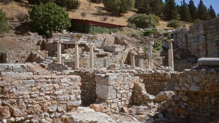 Ancient stone ruins and classical columns in a soft blurred focus on a sunlit hillside outdoor background; background backplate copyspace calm.