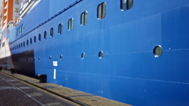 Blue cruise ship hull with round portholes and painted metal panels, defocused and softly blurred outdoor; background copyspace calm.