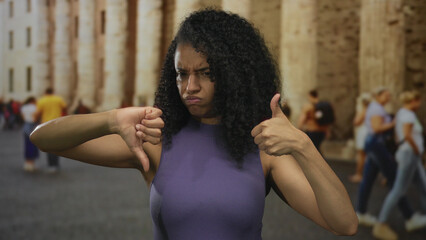 Woman expressing mixed emotions on an old street with columns in the background, surrounded by people in an outdoor urban setting.