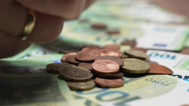 Euro coins fall onto euro banknotes in a macro close-up. Financial concept illustrating savings, small change, spending, cash economy, and everyday money management.