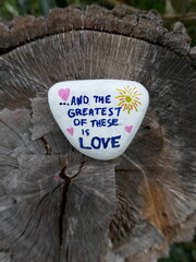 Fototapeta premium Top of old tree stump with greatest of these is love message on kindness rock vertical photo
