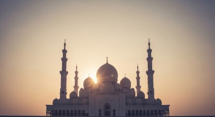Naklejka premium Ornate white mosque silhouette with domes and minarets against a bright sunset