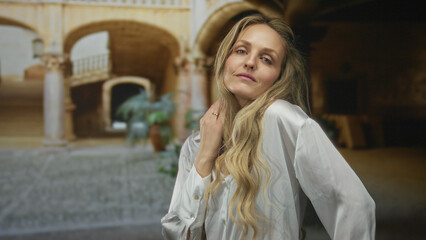 Fototapeta premium Woman standing in historic old town street outdoors with relaxed expression wearing white blouse capturing serene moment
