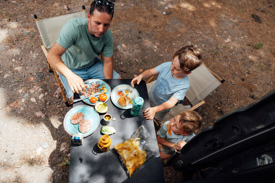 Father and sons enjoying outdoor meal during camper van trip