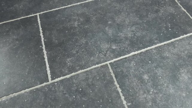 Cleaning process of tile floor with focus on grout lines and dirt buildup in a home setting