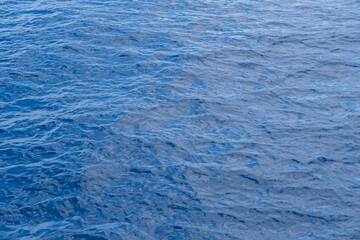 Obraz premium Calm blue water surface with gentle ripples reflecting light, creating a serene aquatic scene in a natural environment