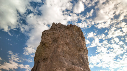 Low angle view of massive rock formation monolith under a dynamic sky