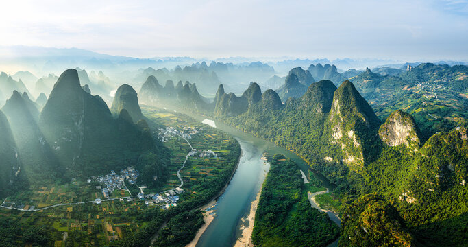 Breathtaking aerial view of the Li River winding through karst mountains and rural villages in Guilin, China during a misty morning.