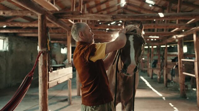 Man grooming and taking care of a horse on a rural ranch. Authentic countryside lifestyle scene showing human and animal connection, agriculture, and outdoor work.