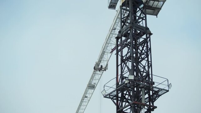 Tower crane mast and jib against clear sky at construction site