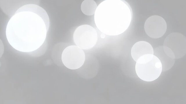 Soft focus bright white bokeh circles and tiny specks on a blurred grey background