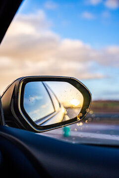 A car's rear view mirror reflects the sun