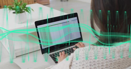 Naklejka premium Typing Korean woman in knit sweater using laptop spreadsheet on sofa with green waveform overlay