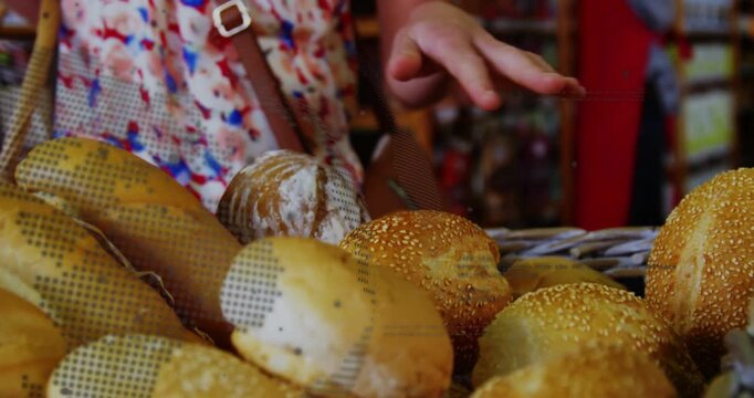 Foreground bread basket, shopper hand moving down above, touching seeded rolls, selecting, buying