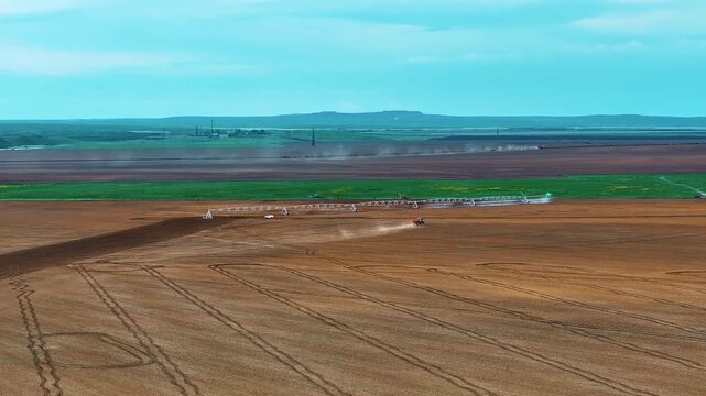 Aerial footage of farmland with an operating center-pivot irrigation system. The panoramic view highlights the vast scale of the fields, modern irrigation methods.
