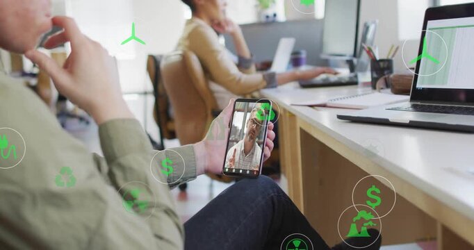 Foreground man holding phone and watching live call, animated green icons marking energy chart