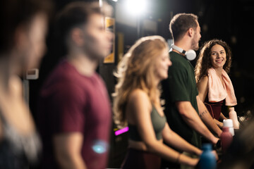 Group of fitness enthusiasts workout together in a gym during evening hours while sharing smiles and motivation