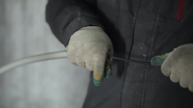 Worker pulling electrical wire through corrugated conduit