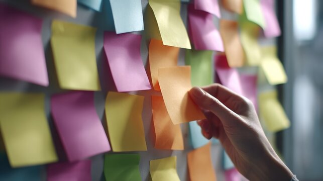 Planning and Organization: A hand reaches to select a sticky note from a vibrant array, symbolizing the essential role of planning and organization in life and business. 