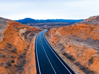 Curved road through rocky landscape in a remote area during the daytime showing mountains in the distance