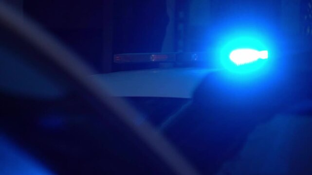 Close-up video of flashing emergency service lights at night. Intense blue and red signals create abstract reflections and motion blur, conveying urgency, alert, and public safety atmosphere.