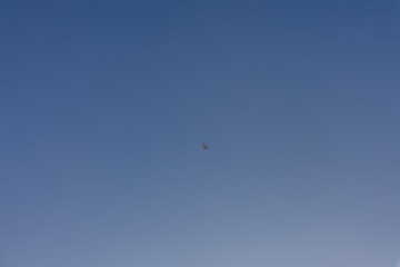 Fototapeta premium Airplane flying high in clear blue sky, copy space