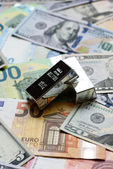 A silver bar, white metal against a backdrop of money, as a concept for the sales. A silver bar