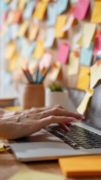 A desk with a laptop, a pencil holder, and a potted plant. The desk is covered in colorful sticky notes
