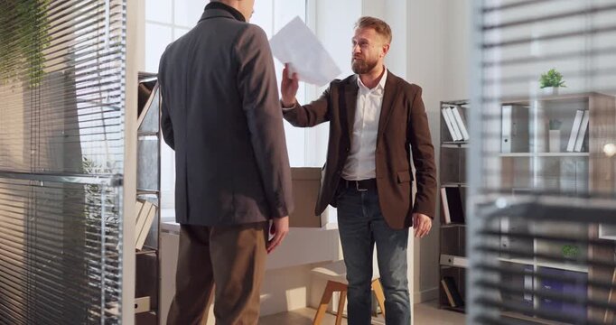 Manager and employee in office dismissal conflict. Belongings go into a box as a layoff meeting sparks serious argument and decisions. Strong concept of workplace stress and job termination.