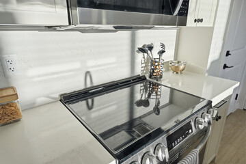 Shiny white stove top with a silver handle and a black knob