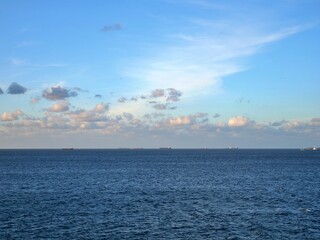 Obraz premium Multiple Cargo Ships on Open Blue Sea Horizon Under Cloudy Sky 