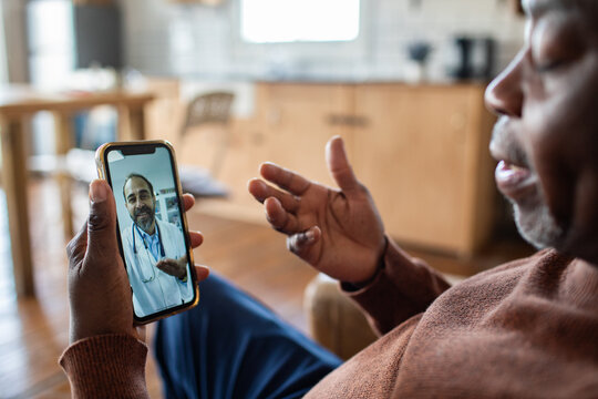 Senior man on telehealth video call with doctor at home